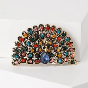 Macro detail of vintage gold peacock brooch with colorful crystals on white background