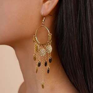 Détail de boucles d'oreilles dorées à franges avec disques en métal martelé