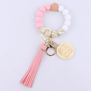Detail of pink silicone bead bracelet with MAMA engraved gold charm and stylish PU tassel