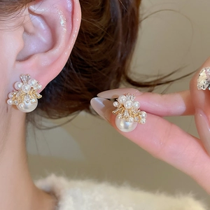 Close-up of elegant gold flower earrings with pearls and crystals on a model's ear