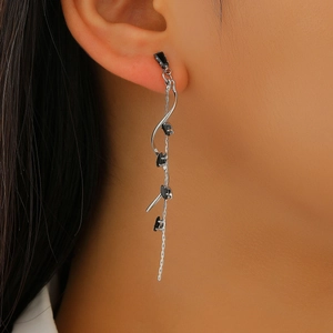 Close-up of model wearing silver tassel earrings with black stones and zircon details