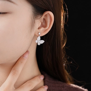 Close-up of a silver butterfly earring with shimmering cubic zirconia on a female model