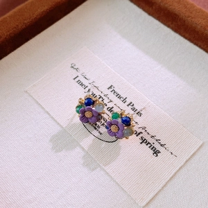 Macro detail of vintage floral earrings with purple crystals and gold metal accents