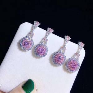 Macro shot of pink crystal drop earrings with sparkling zircon halos on white jewelry stand