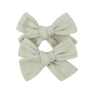 Detailed view of beige lace embroidered bow hair clips with delicate woven textures