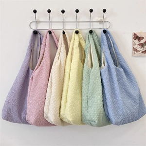 Detailed texture of colorful seersucker tote bags hanging on a white wall rack