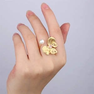 Detail of 18k gold open ring featuring a delicate shell flower and white pearl