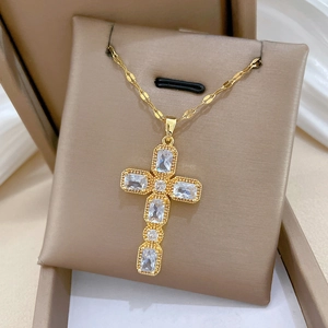 Gros plan détaillé du pendentif croix en titane doré avec cristaux dans son écrin à bijoux