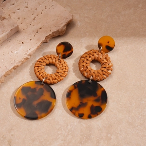 Detailed macro of bohemian resin circle earrings with woven rattan textures and amber finish