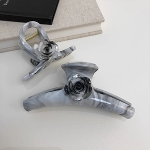 Detail of gray marble hair claws with black camellia flowers in two different sizes
