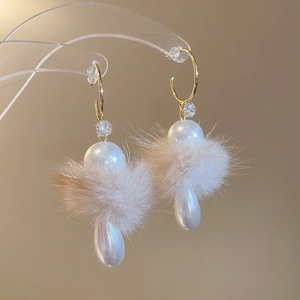 Detail view of C-shaped pearl earrings with soft fur balls and sparkling zircons