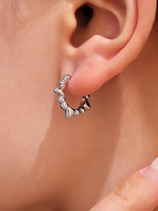 Vue macro d'une boucle d'oreille créole argentée à pointes style punk rock sur le lobe