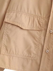 Gros plan d'une chemise tissée kaki avec une poche à rabat et des détails de boutons