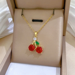 Detail of cherry pendant necklace with red and green gems in a premium jewelry box
