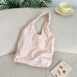 Detailed view of pink floral canvas tote with brand label on a cozy white sofa