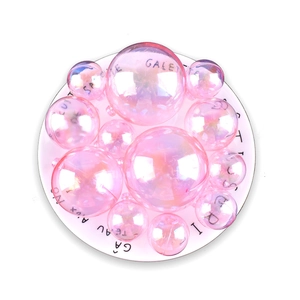 Iridescent pink holographic cake decoration balls in various sizes on a white plate