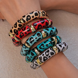 Close-up of stacked acrylic leopard print bangles with gold spacers on a female wrist