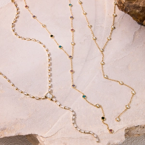 Detailed view of three golden Y-shaped necklaces with zircon and colorful gemstone accents