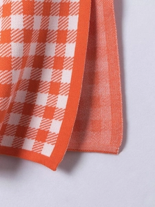 Detail of orange and white houndstooth knit fabric texture with high quality stitching