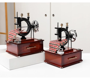 Detailed close-up of retro sewing machine music box featuring miniature iron and fabric