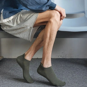Detail view of olive green mesh cotton socks worn by a model in a casual sitting pose