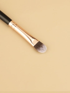 Macro shot of flat tongue-shaped concealer brush with rose gold ferrule and black handle