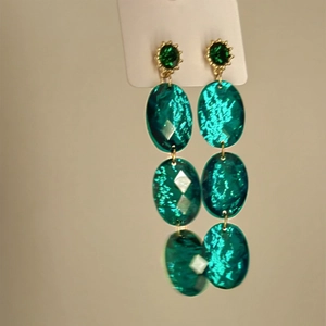 Close-up of vintage emerald geometric drop earrings with gold plated triple link design