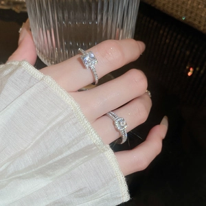 Detail of elegant silver zircon geometric rings worn while holding a glass cup