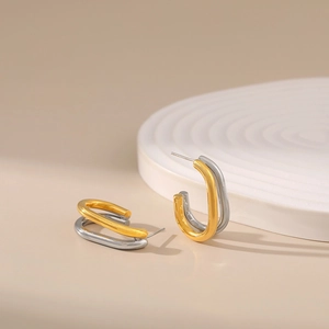 Minimalist C-shaped two-tone 18K gold plated earrings on a white textured display tray