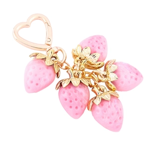 Detailed close-up of pink strawberry keychain with golden leaves and a heart hook