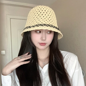 Close-up of beige straw bucket hat with intricate black lace trim and hollow texture