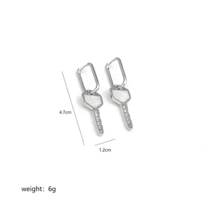 Detail view of silver key-shaped earrings with hexagonal head and white glossy inlay