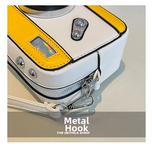 Detail shot of silver metal hardware and buckle on a camera-shaped crossbody bag