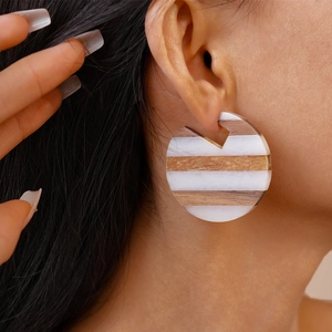 Close-up of geometric round wood resin earrings with brown and white striped texture