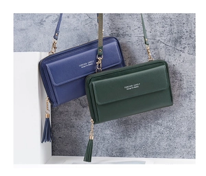 Detail of blue and green crossbody phone bags with leather grain and tassel accents