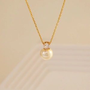 Elegant gold snake chain necklace featuring a round pearl pendant and sparkling zircon