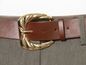 Gros plan d'une ceinture en cuir marron avec boucle dorée sur un pantalon vert