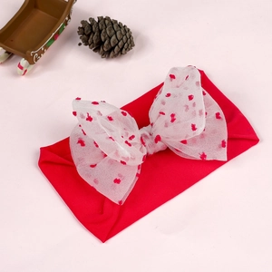 Detail of red knitted infant headband featuring a large white tulle bow with red hearts