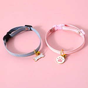 Detailed view of blue and pink denim pet collars with bone and footprint shaped pendants