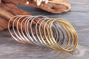 Macro view of minimalist gold, silver, and rose gold bangles with polished and matte finishes