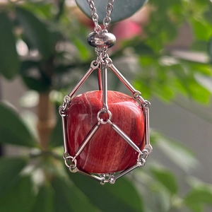 Macro shot of a red square natural crystal pendant secured in a silver mesh metal cage