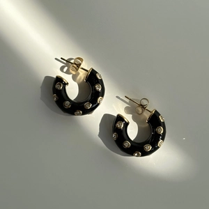 Detail of C-shaped black enamel hoop earrings with inlaid cubic zirconia and gold accents