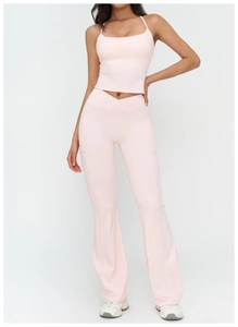 Detail of pink yoga set featuring cross-waist flared pants and racerback crop top
