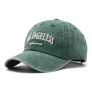 Detailed close-up of dark green washed cotton baseball cap with vintage white embroidery