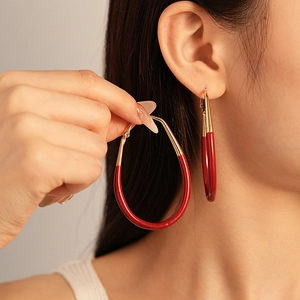 Exaggerated burgundy and gold teardrop hoop earrings in a minimalist retro design