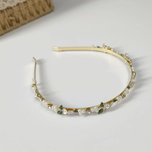 Detail of floral headband with white enamel flowers, pearls and green leaves on gold frame