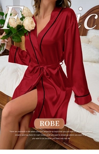 Detail of red satin robe with black trim and waist tie in a cozy bedroom setting