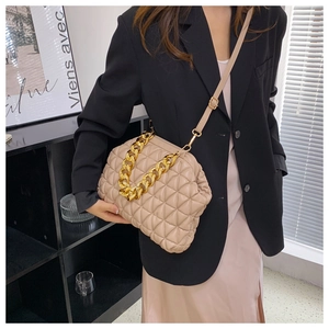 Chic beige quilted shell bag with thick metal chain strap worn by a fashion model