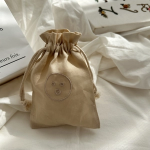 Close-up of linen drawstring storage bag with embroidered smiley face and cotton ropes