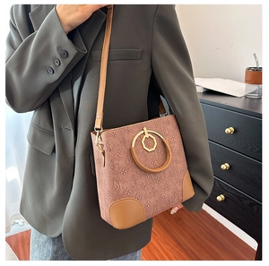 Detail of printed bucket bag with metal handle, floral pattern, and brown PU leather trim